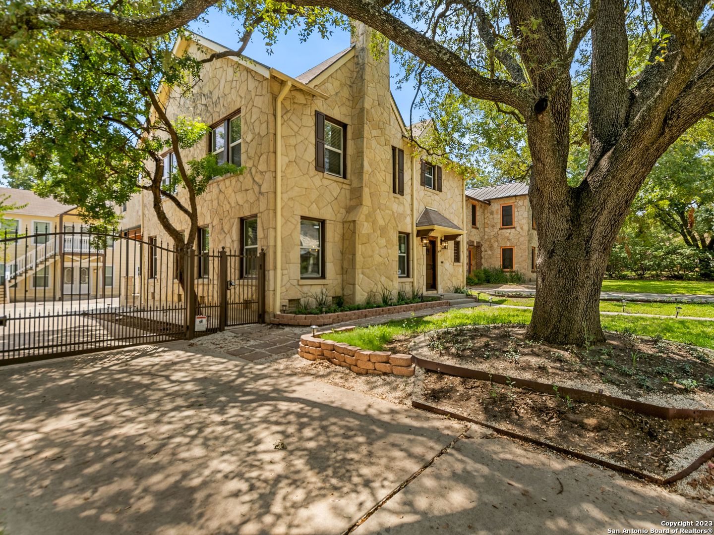 This H.C. Thorman-stone home has been exquisitely renovated. It seamlessly blends contemporary living with the charm of Olmos Park's historical ambiance. The house showcases an array of enhancements and modernizations, including a spacious, newly designed master suite and an updated master bathroom featuring luxurious rain head showers, a separate tub, double vanities, and energy-efficient windows that have been installed throughout the entire residence, the open-concept layout creates a sense of spaciousness, while the electrical  system has been completely updated, remote-controlled security gates, wireless thermostats, and a remodeled, chef-inspired kitchen boasting stainless steel appliances, quartz countertops, and ample cabinet space. Additionally, a new HVAC system has been installed for your comfort. Beyond the main house, there are two guest suites located in a separate structure at the rear of the property, providing versatile spaces ideal for hosting guests, establishing a home office, or setting up a personal gym. A magnificent mature oak tree graces the front yard, while the backyard features a low-maintenance xeriscape design. This residence falls within the Alamo Heights Independent School District and benefits from convenient access to a nearby bus stop. Enjoy easy proximity to a variety of dining and shopping options, making this property the perfect blend of modern convenience and classic elegance in Olmos Park.