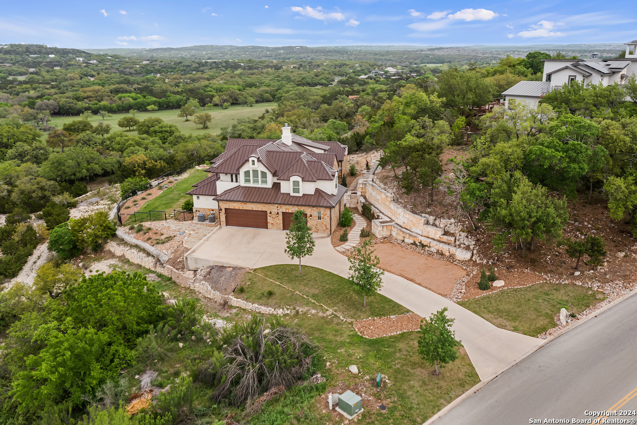 Step into your sanctuary nestled in the serene embrace of the hill country's enchanting landscape! This captivating abode, nestled within the prestigious Canyons at Scenic Loop, offers a symphony of luxury and tranquility. Spanning 5,058 square feet across two levels, this residence boasts 4 bedrooms, 4.5 bathrooms, an office/library adorned with bespoke built-ins, and a delightful bonus game room adjacent to the ample 3-car garage. As you cross the threshold, you'll be greeted by the heart of the home, a resplendent great room adorned with a majestic fireplace, seamlessly merging with a gourmet kitchen boasting top-of-the-line appliances, including a dedicated ice machine. The kitchen's sprawling island beckons gatherings and culinary adventures, promising cherished moments with loved ones. With soaring ceilings gracing each room, this home exudes a sense of spaciousness and elegance, while retaining an inviting warmth. Step outside onto the back patio and behold the expansive vista of lush hill country panoramas, beckoning you to unwind in nature's embrace. Situated on 1.15 acres, this property offers boundless opportunities to craft your own hill country haven, where dreams take flight amidst breathtaking beauty.