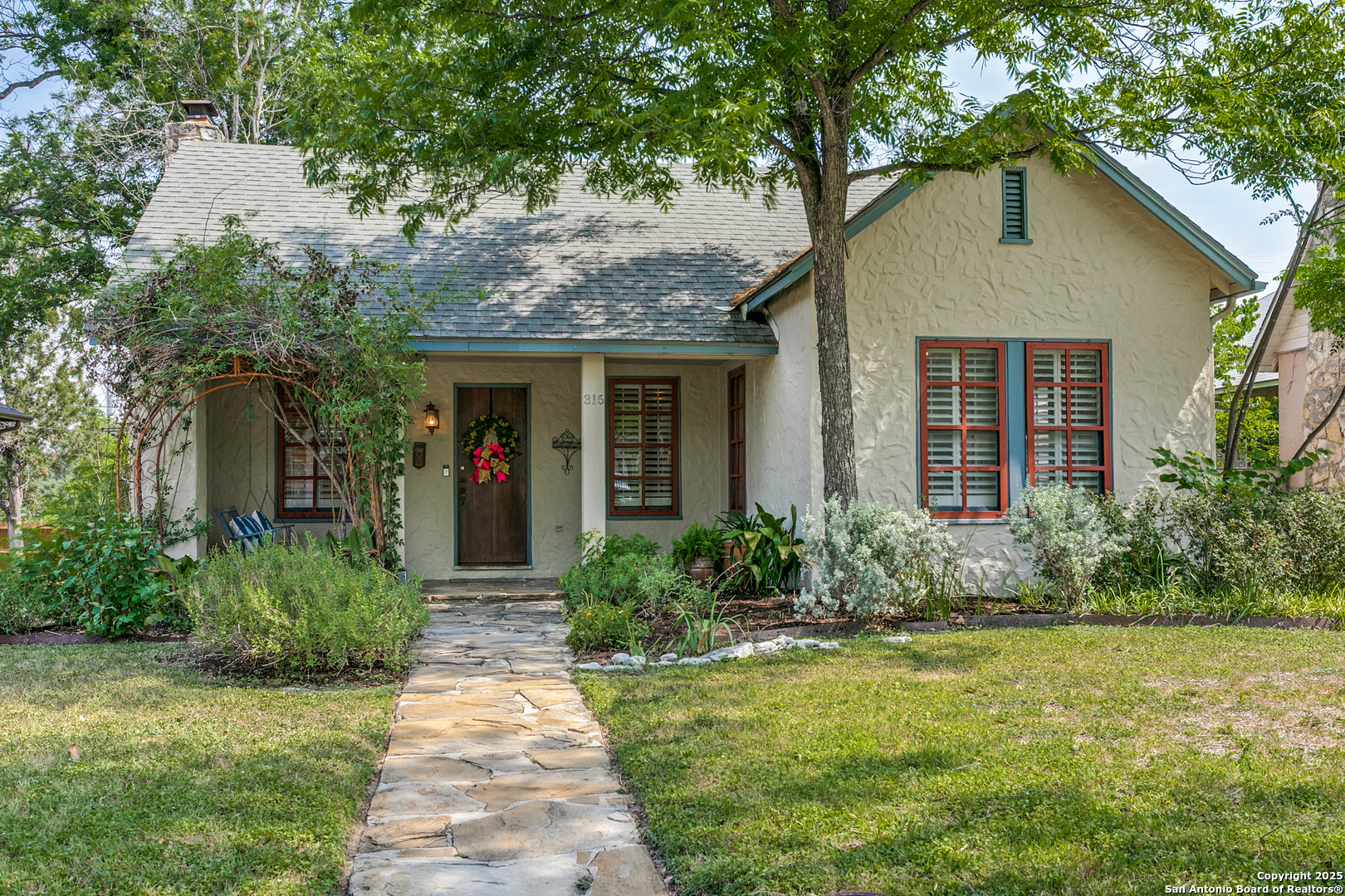 This storybook Craftsman home is charming, with many original features still in place. The welcoming front porch hides behind a lovely climbing rose bush. The cozy living room with plaster fireplace, hardwood floors, and plantation shutters opens to formal dining. The dining room has French doors to the side deck. The cute eat-in kitchen  has a gas stove and stainless fridge. There are three bedrooms and two bathrooms. Large back deck, greenhouse, small inviting garden.