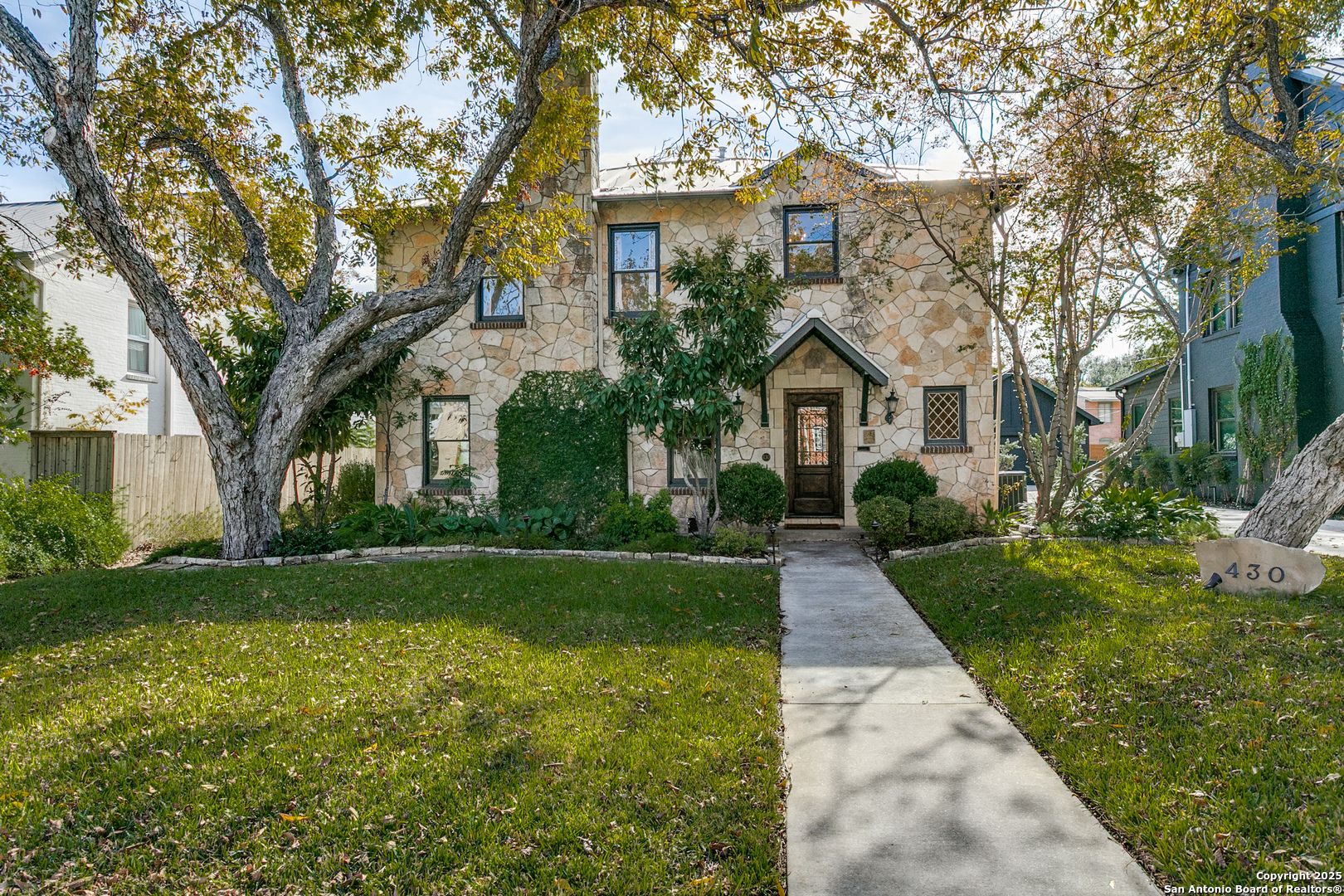 This charming Olmos Park home welcomes you with exceptional curb appeal, framed by stately shade trees. Step inside to discover beautiful wood floors that flow gracefully throughout. The entry opens to a light-filled formal living room featuring a gas fireplace, built-in bookcases, and an elegant ambiance perfect for relaxing or entertaining. Just beyond, the adjacent dining room offers an ideal setting for hosting memorable gatherings. The updated island kitchen has appealing design, boasting abundant storage, a professional-grade range, Sub Zero refrigerator, a walk-in pantry, and thoughtful finishes throughout. A convenient pass-through butler's pantry adds even more storage and functionality. The inviting family room offers serene views of the Zen garden, a second fireplace, and direct access to two covered stone patios-perfect for seamless indoor-outdoor living. Upstairs, you'll find two comfortable secondary bedrooms, an updated hall bath, and a truly dreamy primary suite. The spacious primary retreat features two generous walk-in closets and a spa-inspired bath with a soaking tub, over-sized pedestal sink, and a separate shower. Completing the property is a detached two-car garage.